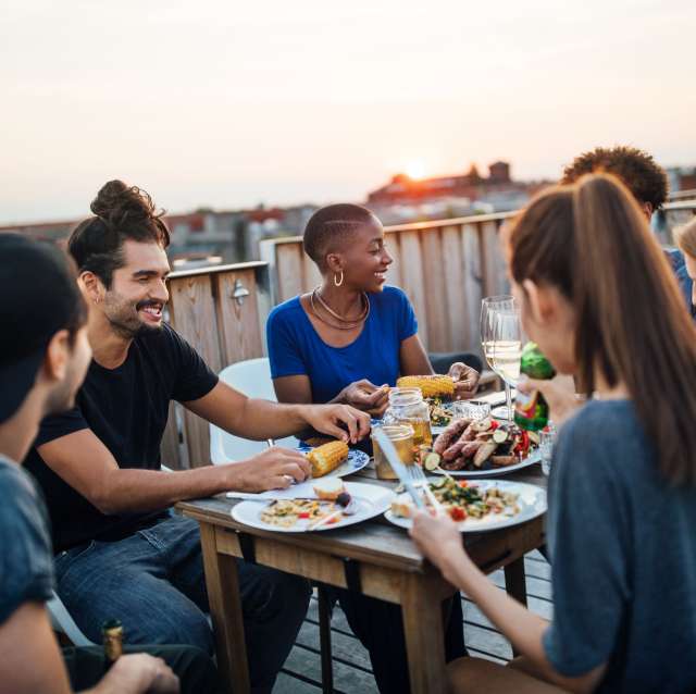 junge-menschen-sitzen-am-tisch-und-essen-vergnuegt